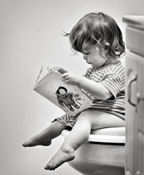 bambino che legge un libro seduto in bagno sul wc